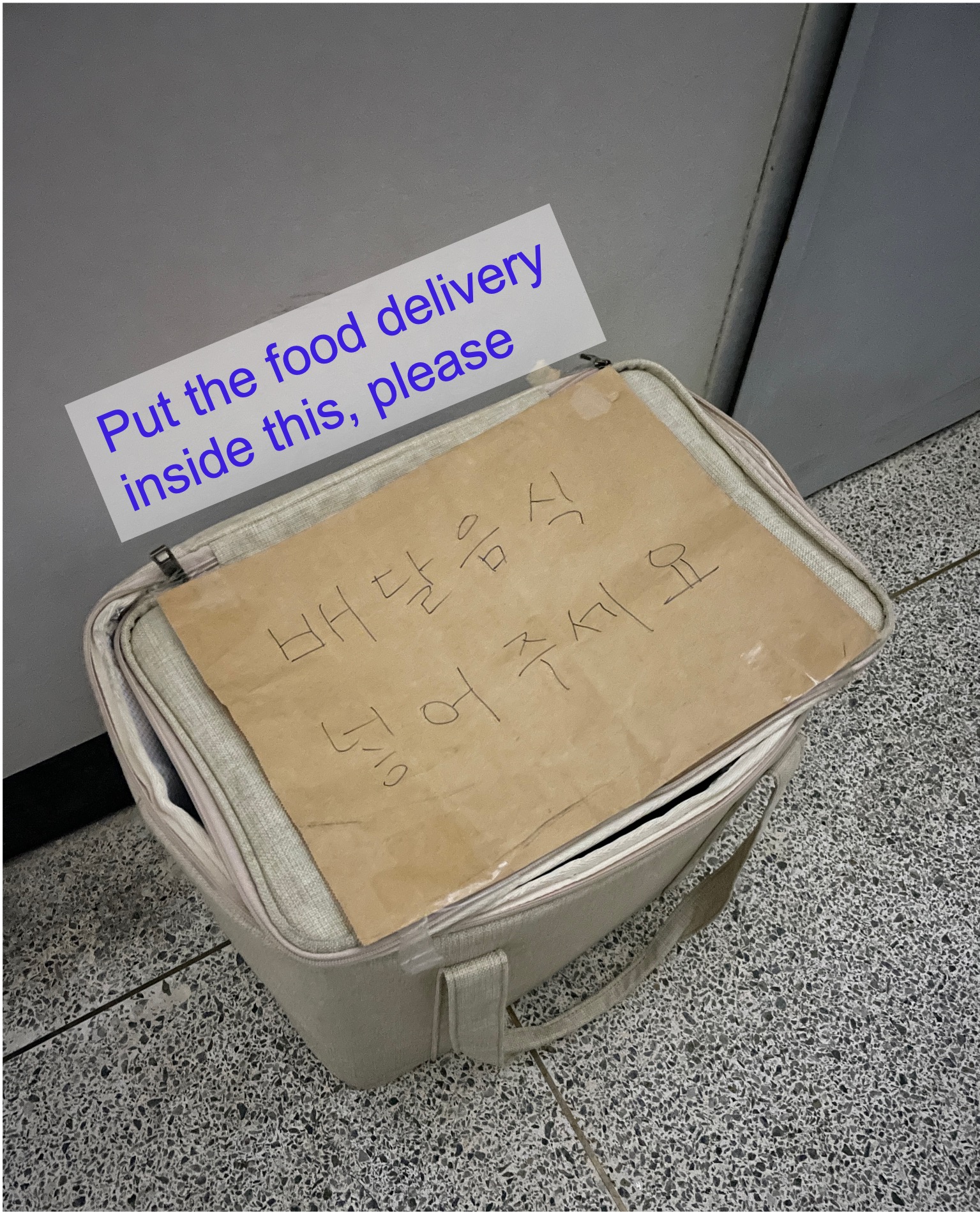 In front of an entry door to a flat, a bag is placed to put food delivery inside. On a paper is written in Korean: Leave it at the doorstep and don’t ring the bell.